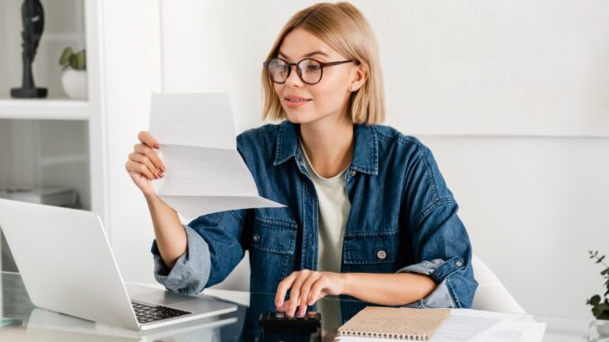 Young caucasian woman paying domestic bills, making calculations at home desk. salaire 1500 net