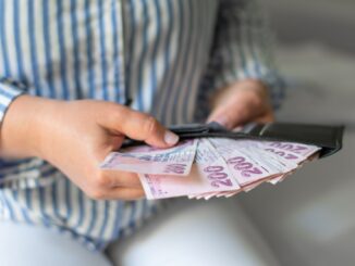 Leather wallet with money in the hands of a woman who takes out a pack of 200 Turkish lira bills
