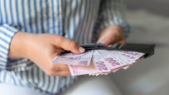 Leather wallet with money in the hands of a woman who takes out a pack of 200 Turkish lira bills