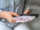 Leather wallet with money in the hands of a woman who takes out a pack of 200 Turkish lira bills