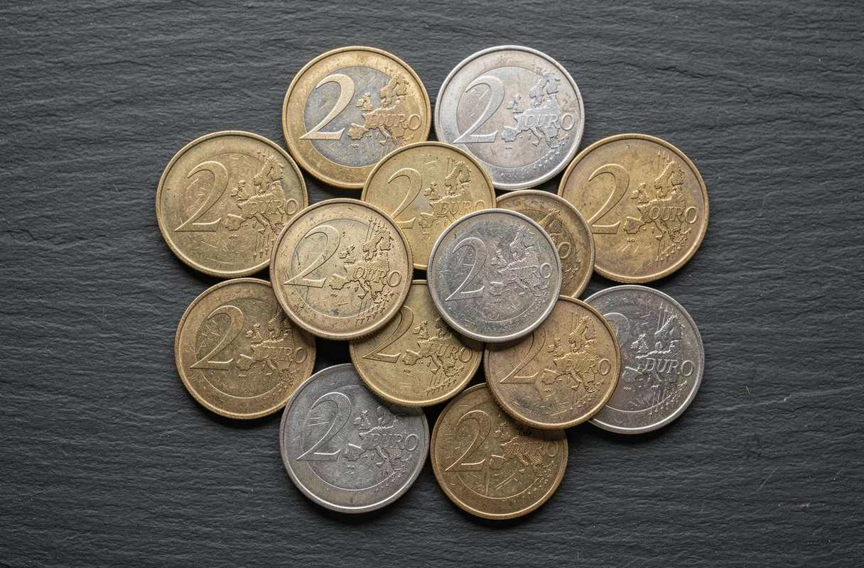 Vue macro de plusieurs pièces de 2 euros rares de différents pays européens disposées sur une surface en ardoise sombre, montrant les détails de frappe et les marques d'atelier
